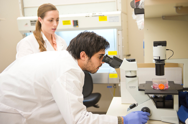 Two trainees working with a microscope in a research lab.