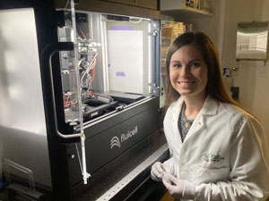 A lab researcher uses a pipette to test for biomarkers.
